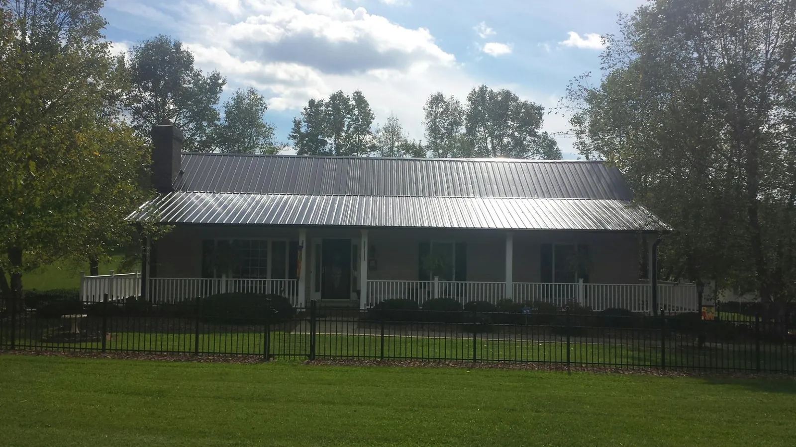 Gray metal roof on a brick ranch with a full width front porch — Gutter Guard Installation work by our crew in Island Park